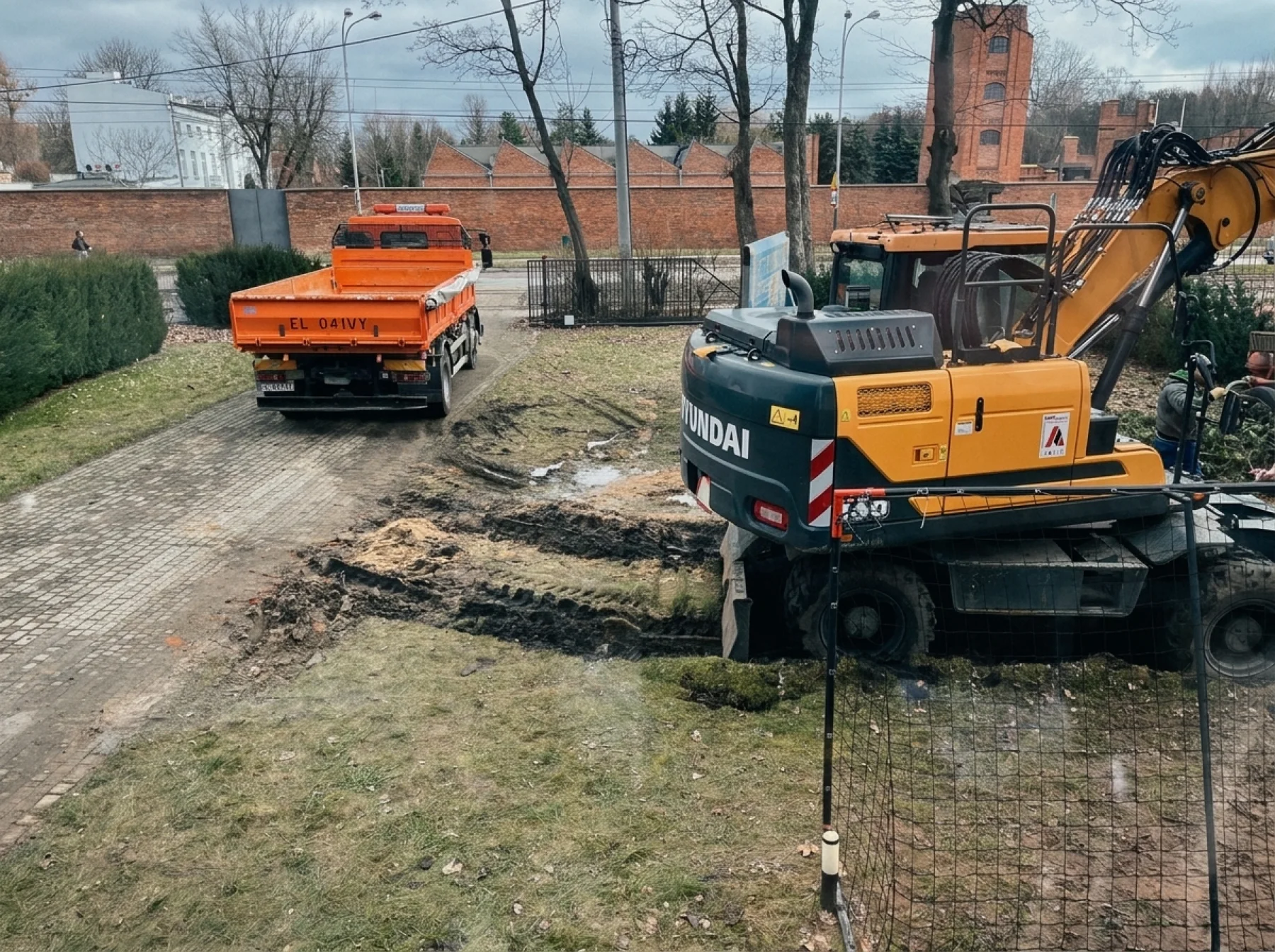 Utility workers and an excavator digging up the ground outside to reach the burst line.